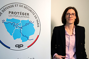 Aurélie Lebourgeois posant à côté du logo du secrétariat général de la zone de défense et de sécurité de Paris (SGZDS)