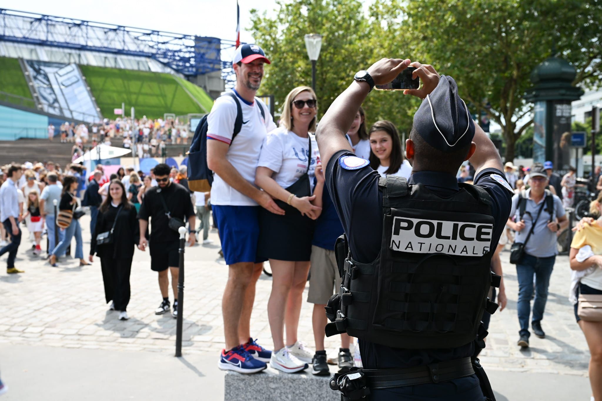 Un policier prend en photo des touristes devant l'Arena de Bercy