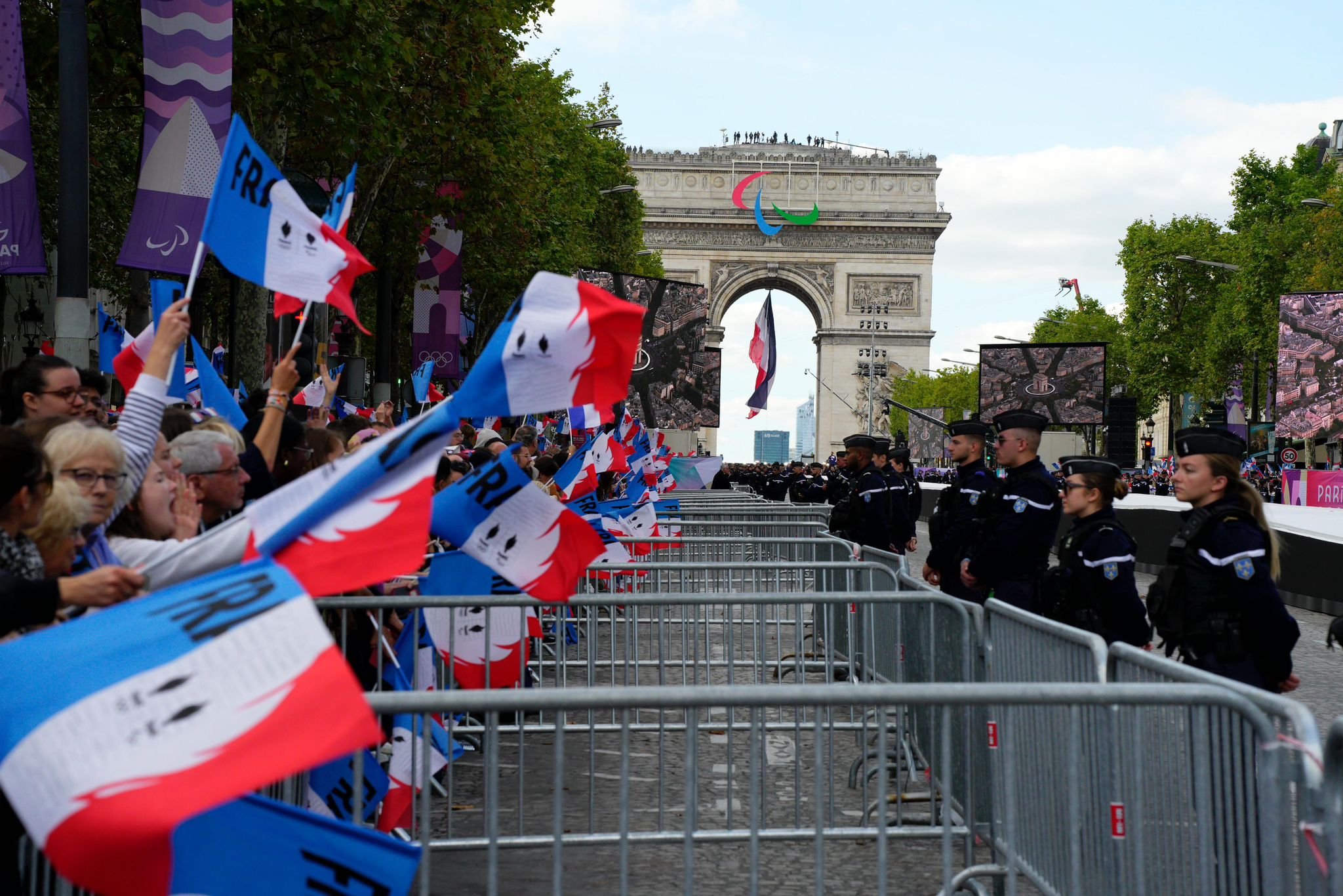 Gendarmes face à face avec les spectateurs agitant des drapeaux français