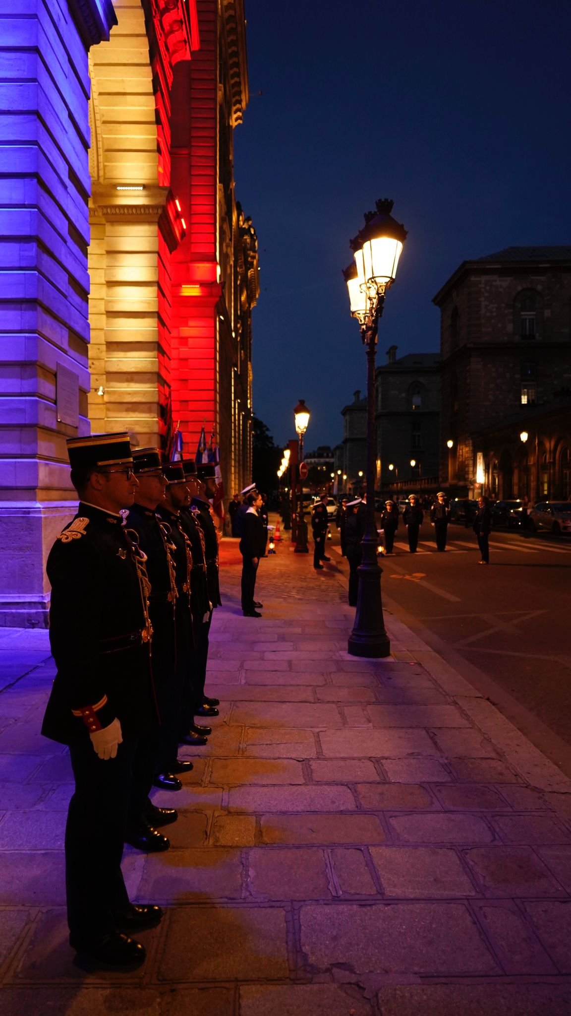 Agents en uniforme devant la préfecture de Police éclairée en bleu-blanc-rouge
