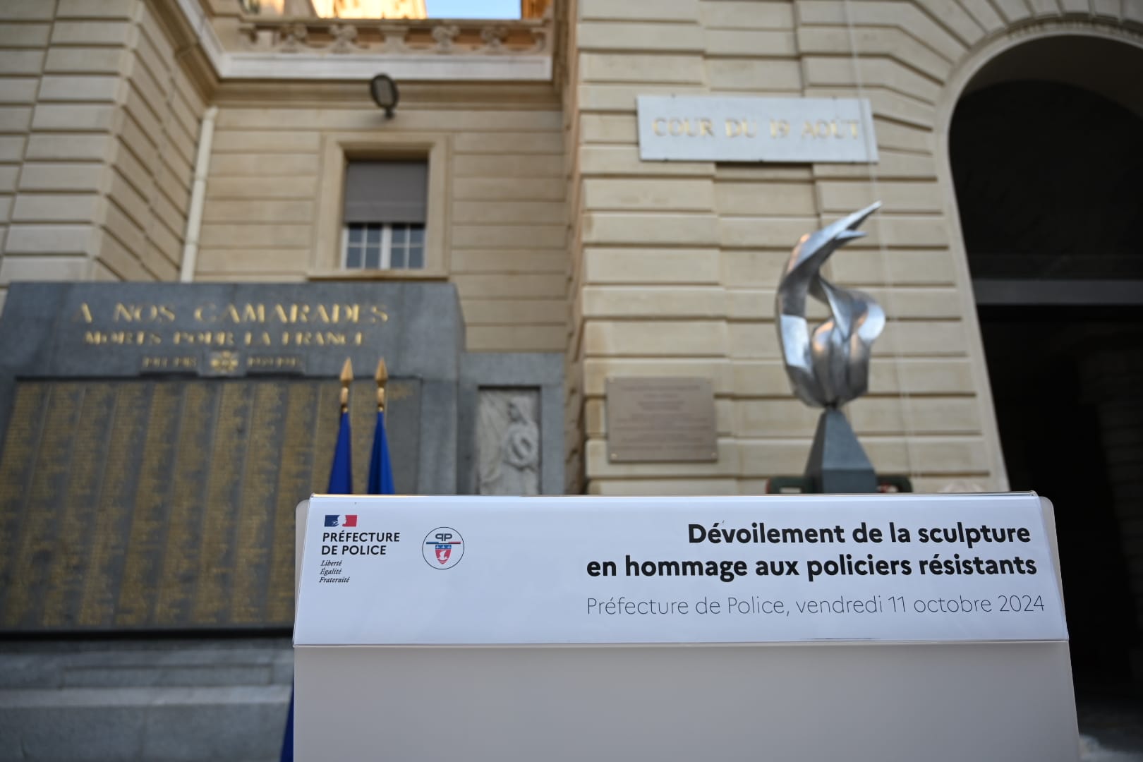 Transcription textuelle : "Dévoilement de la sculpture en hommage aux policiers résistants - Préfecture de Police, vendredi 11 octobre 2024"