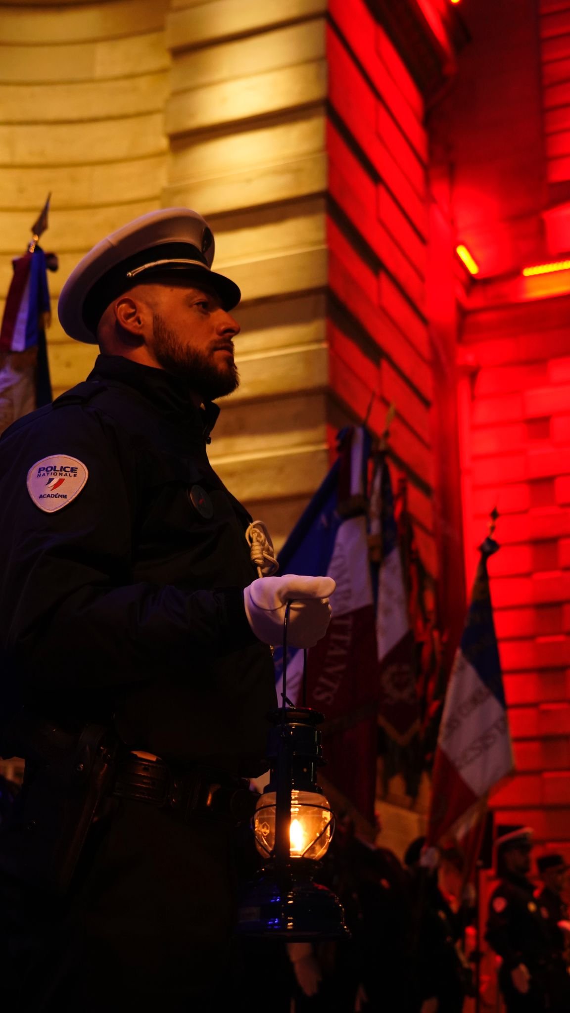 Agent à l'entrée de la préfecture de Police, tenant une lanterne pour la veillée d'hommage