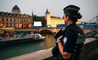 Une policière vue de dos regarde la Seine durant les préparations de la cérémonie d'ouverture